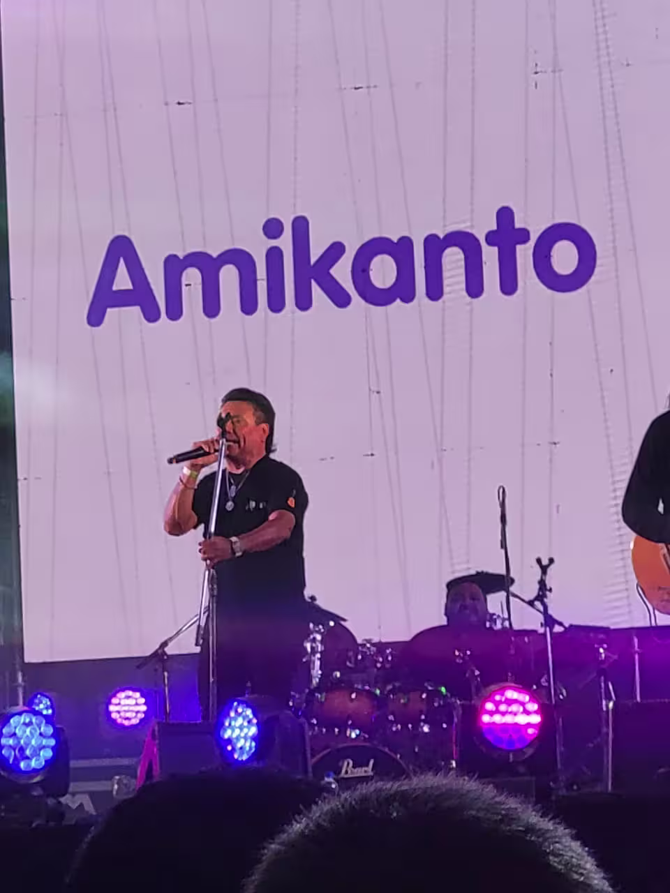 Julio Ortiz cantando con un micrófono en la mano mientras mira al público.