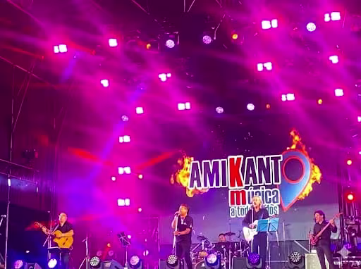 Cantantes de Amikanto mirando al público en el escenario con luces azules.