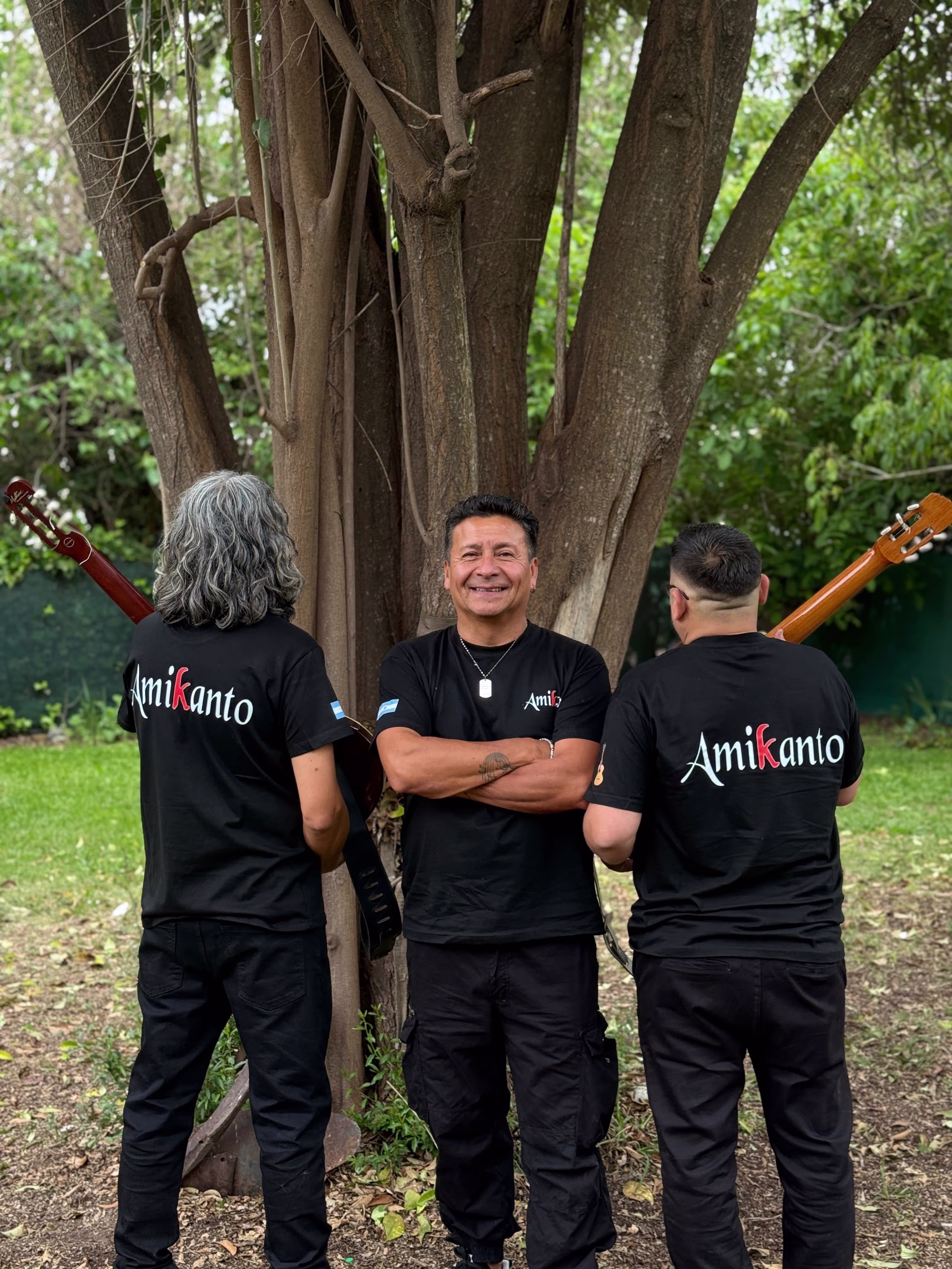 Integrantes de Amikanto posando, con dos miembros mostrando la marca del grupo en la parte trasera de la remera.