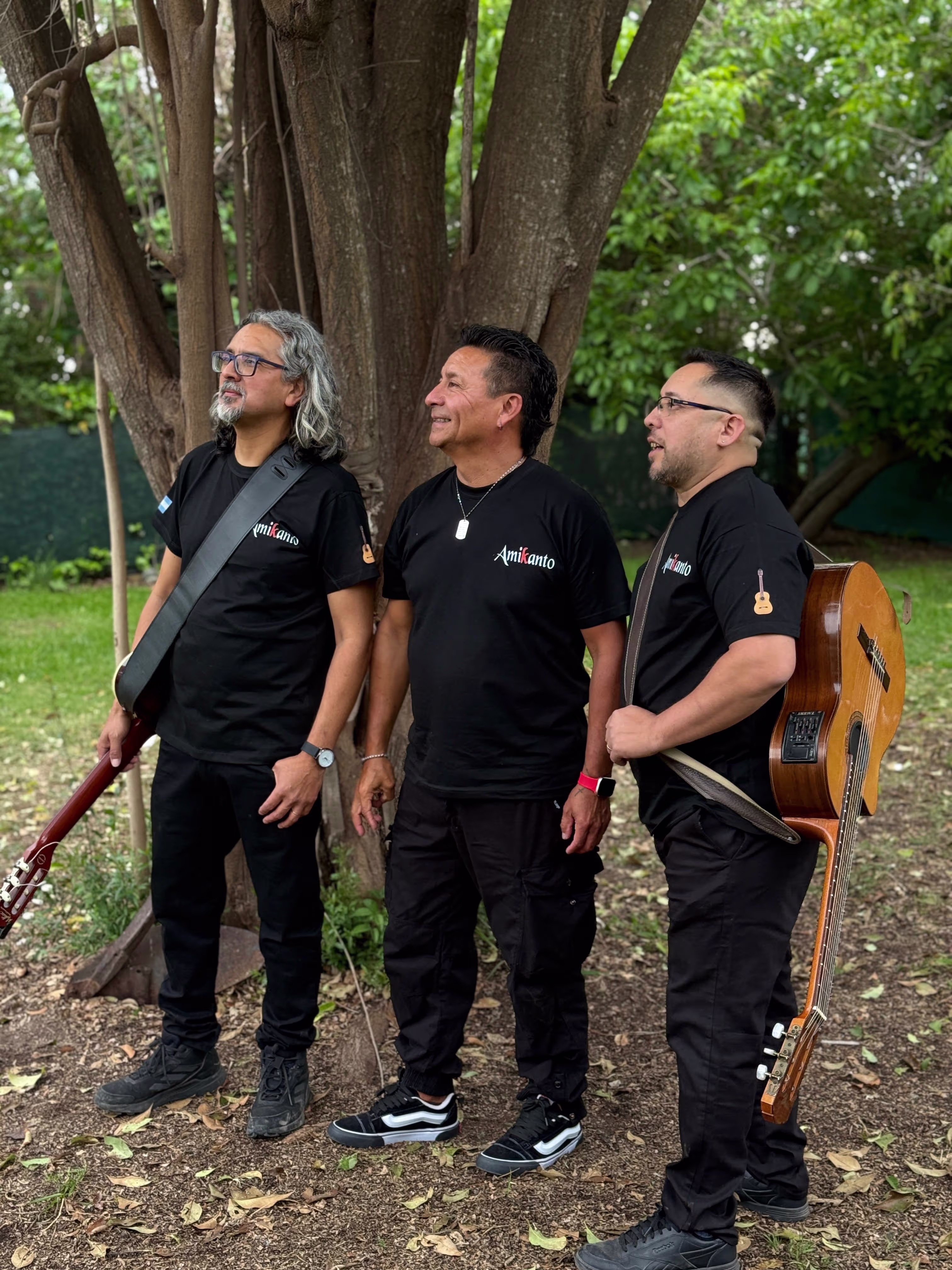 Los tres integrantes de Amikanto posando de perfil mientras miran hacia la izquierda, en un entorno arbolado