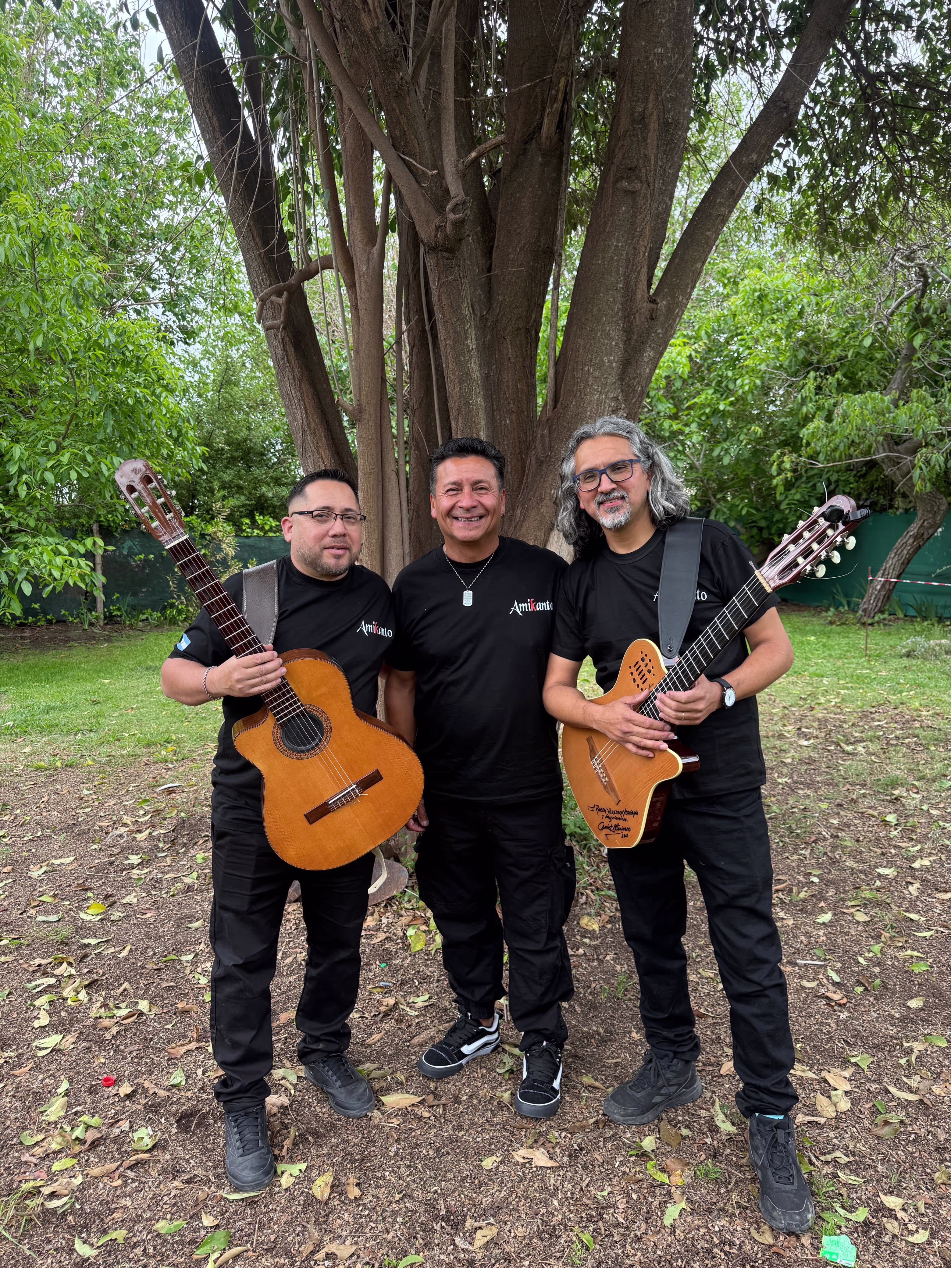 Los tres integrantes de Amikanto posando juntos, dos de ellos sosteniendo guitarras.